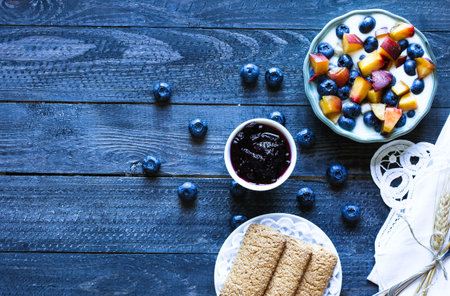 Healthy Breakfast with blueberries and banana yogurt, biscuits, marmalade, coffee and peaches over a...