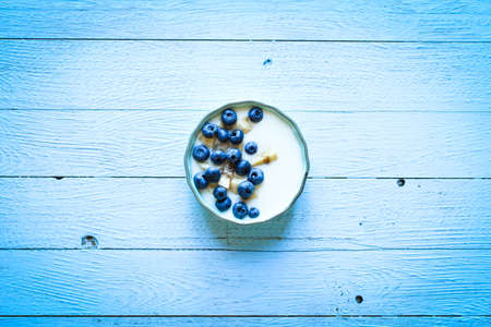 Healthy Breakfast with blueberries and banana yogurt, biscuits, marmalade, coffee and peaches over a light wooden background.の写真素材