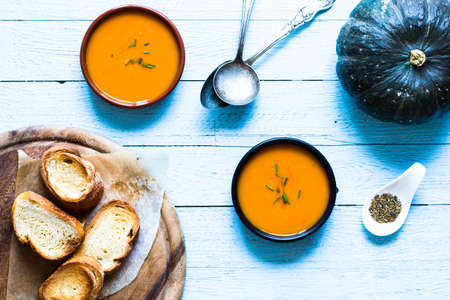 Vegan Creamy Delicious  Pumkin Soup with fresh vegaetables and sliced of bread over a wooden background.の写真素材