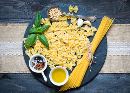 Italian pasta with pesto sauce made with basil leafs, pine nuts, fresh garlic and olive oil over an old wood background, top viewの写真素材