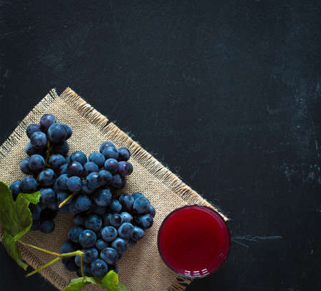 Dark grape and juice over an old wooden  backgroundの写真素材