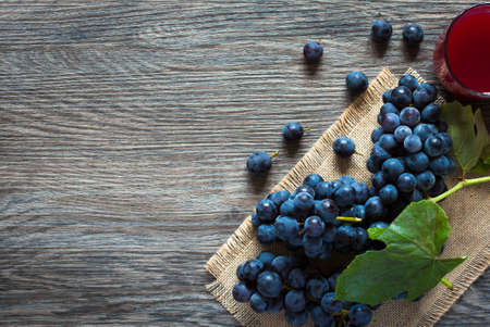 Dark grape and juice over an old wooden  backgroundの写真素材