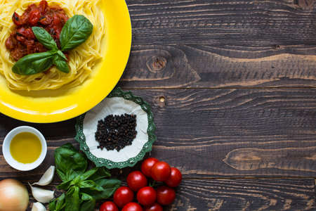 Italian food cooking ingredients for tomato pasta with vegetables and spices. Top view on wooden backgroundの写真素材