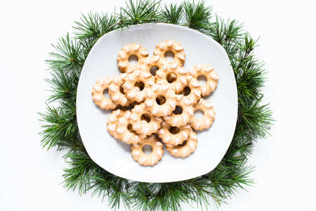 Christmas biscuits on a dish on clear background with a lot of seasonal objects on white table.の写真素材