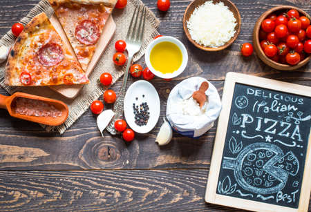 Hot Italian pizza with melting tomato,pepperoni and cheese on a rustic wooden table.の写真素材