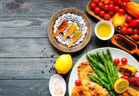 Grilled chicken breast with fresh vegetables on wooden backgroundの写真素材