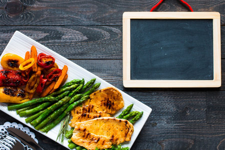 Grilled chicken breast with fresh vegetables on wooden backgroundの写真素材