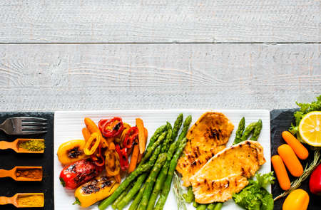 Grilled chicken breast with fresh vegetables on wooden backgroundの写真素材