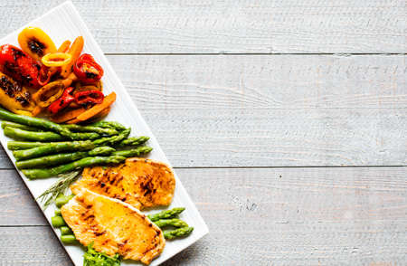 Grilled chicken breast with fresh vegetables on wooden backgroundの写真素材