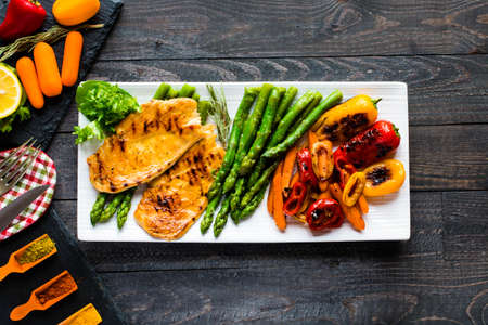 Grilled chicken breast with fresh vegetables on wooden backgroundの写真素材