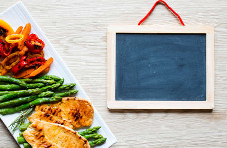 Grilled chicken breast with fresh vegetables on wooden backgroundの写真素材