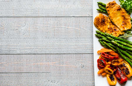 Grilled chicken breast with fresh vegetables on wooden backgroundの写真素材