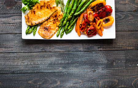 Grilled chicken breast with fresh vegetables on wooden backgroundの写真素材