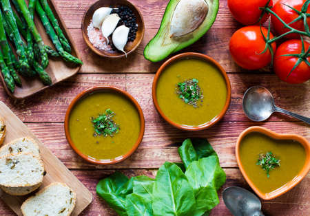 Spinach cream soup with asparagus, croutons and olives, on rustic backgroundの写真素材