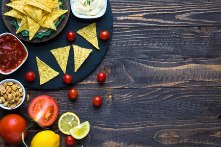 Mexican nachos chips with spicy tomato sauce on wooden backgroundの写真素材