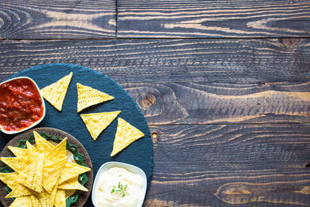 Mexican nachos chips with spicy tomato sauce on wooden backgroundの写真素材