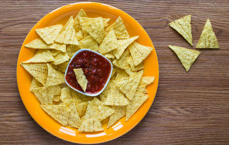 Mexican nachos chips with spicy tomato sauce on wooden backgroundの写真素材
