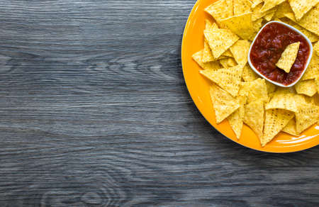 Mexican nachos chips with spicy tomato sauce on wooden backgroundの写真素材