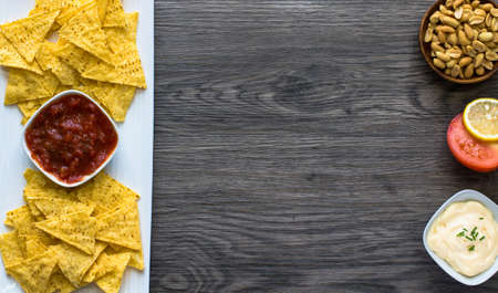 Mexican nachos chips with spicy tomato sauce on wooden backgroundの写真素材