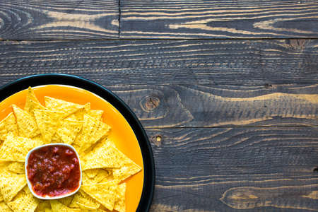 Mexican nachos chips with spicy tomato sauce on wooden backgroundの写真素材