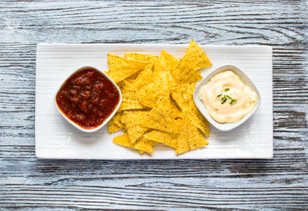 Mexican nachos chips with spicy tomato sauce on wooden backgroundの写真素材