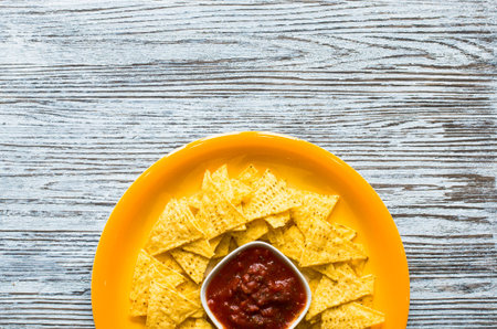 Mexican nachos chips with spicy tomato sauce on wooden backgroundの写真素材