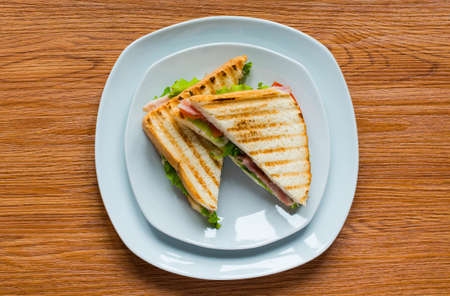 Top view of Healthy Sandwich toast with lettuce, ham, cheese and tomato on a wooden backgroundの写真素材
