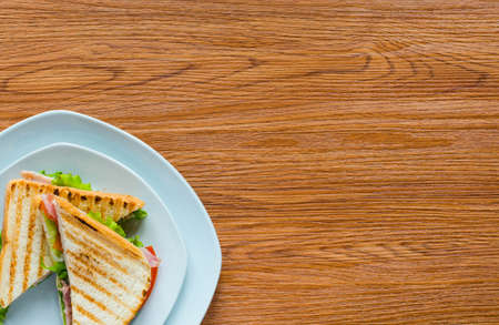 Top view of Healthy Sandwich toast with lettuce, ham, cheese and tomato on a wooden backgroundの写真素材