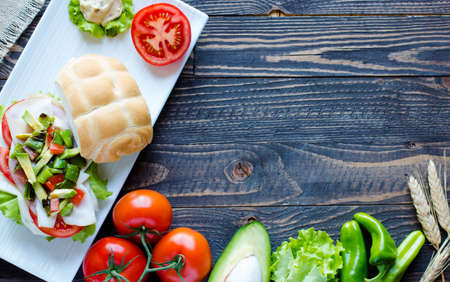 Fresh and tasty sandwich with ham and vegetables, isolated and tomato on wooden backgroundの写真素材