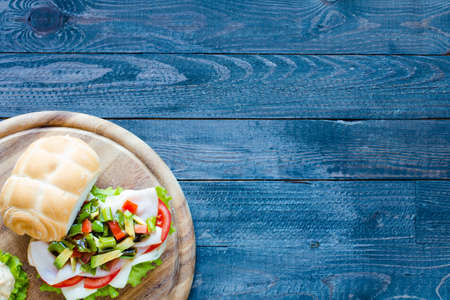 Fresh and tasty sandwich with ham and vegetables, isolated and tomato on wooden backgroundの写真素材