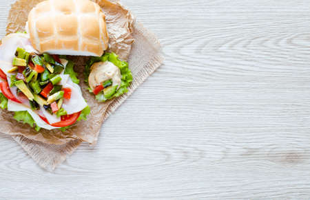 Fresh and tasty sandwich with ham and vegetables, isolated and tomato on wooden backgroundの写真素材