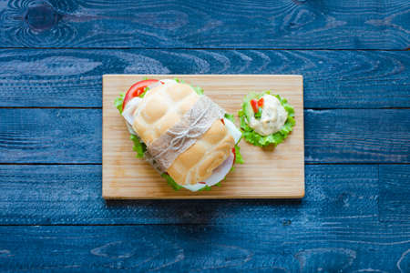 Fresh and tasty sandwich with ham and vegetables, isolated and tomato on wooden backgroundの写真素材