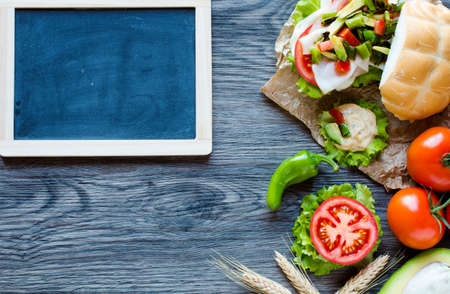 Fresh and tasty sandwich with ham and vegetables, isolated and tomato on wooden backgroundの写真素材