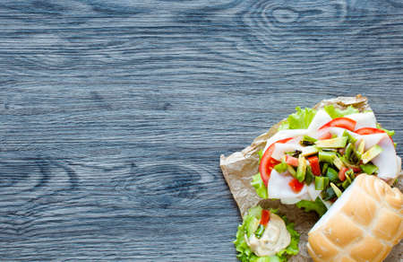 Fresh and tasty sandwich with ham and vegetables, isolated and tomato on wooden backgroundの写真素材