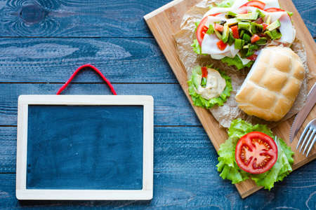 Fresh and tasty sandwich with ham and vegetables, isolated and tomato on wooden backgroundの写真素材