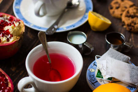 Fruit tea with, lemon, milk,honey,orange, pomegranate and brown sugar, on a wooden backgroundの写真素材