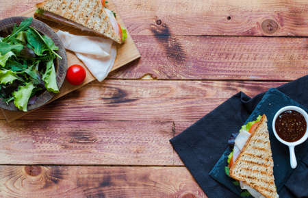 Top view of Healthy Sandwich toast with lettuce, ham, cheese and tomato on a wooden backgroundの写真素材