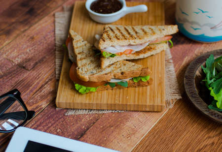 Top view of Healthy Sandwich toast with lettuce, ham, cheese and tomato on a wooden backgroundの写真素材