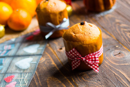 Mini panettone with fruits and Christmas decoration, on different wood background