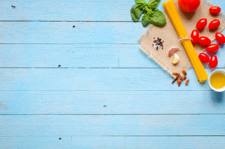 Pasta background. Several types of dry pasta with vegetables,and herbs. On a wooden table. Free space for text . Top viewの写真素材