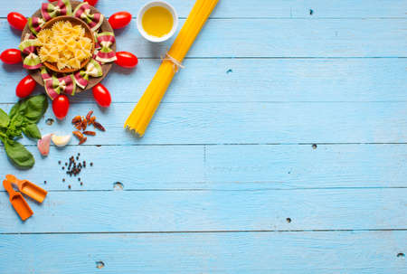 Pasta background. Several types of dry pasta with vegetables,and herbs. On a wooden table. Free space for text . Top viewの写真素材
