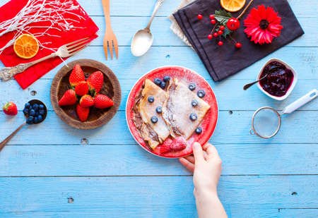 Fresh Strawberries Pancakes or Crepes with berries and chocolate over a wooden tableの写真素材