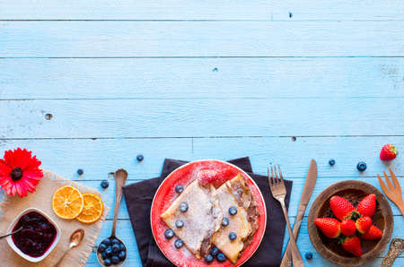 Fresh Strawberries Pancakes or Crepes with berries and chocolate over a wooden tableの写真素材