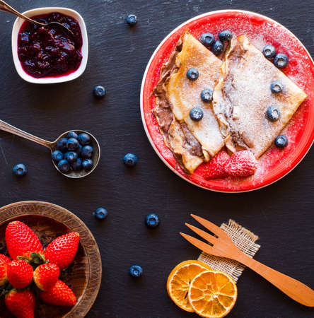 Fresh Strawberries Pancakes or Crepes with berries and chocolate over a wooden tableの写真素材