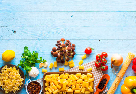 Top view of italian ingredients for spaghetti, with tomato, garlic, mushrooms,parsley, over a wood...