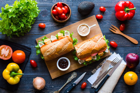 Delicious and Tasty sandwiches with turkey, ham, cheese, tomatoes and salad over a wooden table full...
