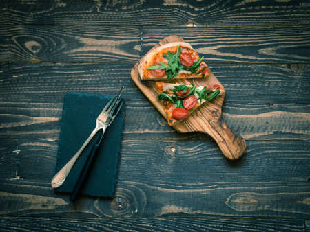 Home maid fresh pizza with tomatoes, rucola and mozzarella cheese over a wooden background. Top view.の写真素材