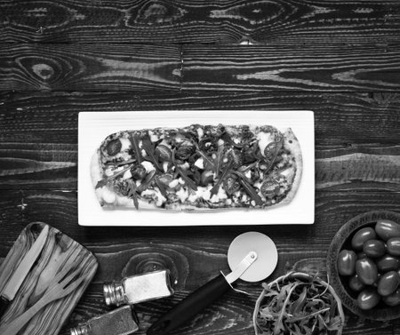 Home maid fresh pizza with tomatoes, rucola and mozzarella cheese over a wooden background. Top view.の写真素材