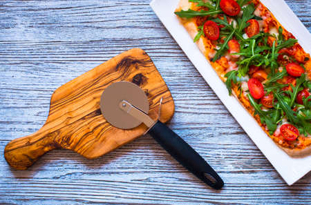 Home maid fresh pizza with tomatoes, rucola and mozzarella cheese over a wooden background. Top view.の写真素材