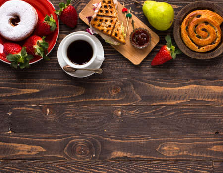 Top view of Healthy Sandwich toast with coffee,donuts, with fruits on a wooden backgroundの写真素材